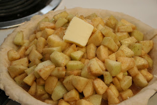 Top apple pie filling with butter before applying top crust