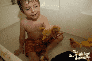 boy playing in bathtub with baby ducklings