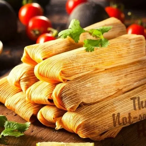 Mexican Pork Tamales Rojos Recipe | The Not So Modern Housewife Pork tamales on a board with salsa and cilantro