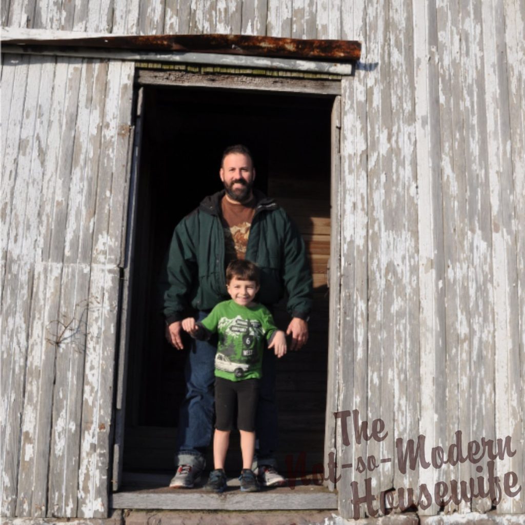 father and son standing in the doorway of an old barn on a homestead