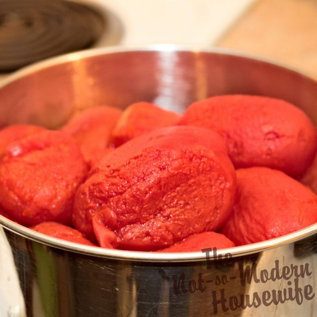 peeled and roasted tomatoes in a stainless steel bowl