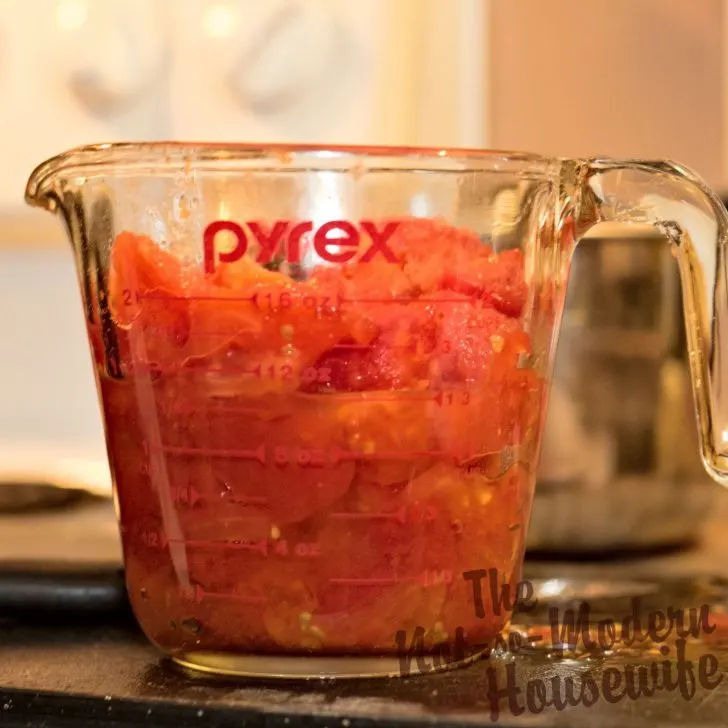 Delicious Restaurant Style Homemade Salsa Recipe with 4 Tips for Water Bath Canning | The Not So Modern Housewife measuring chopped tomatoes for salsa in glass measuring cup - how to can homemade salsa