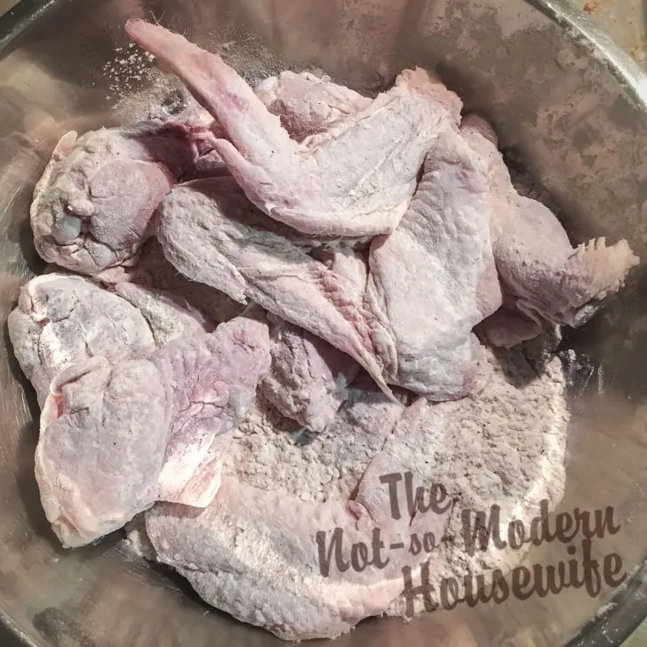 How to Make Delicious Cast Iron Chicken Wings at Home for a Fraction of the Cost | The Not So Modern Housewife Dusting wings in flour - cast iron chicken wings