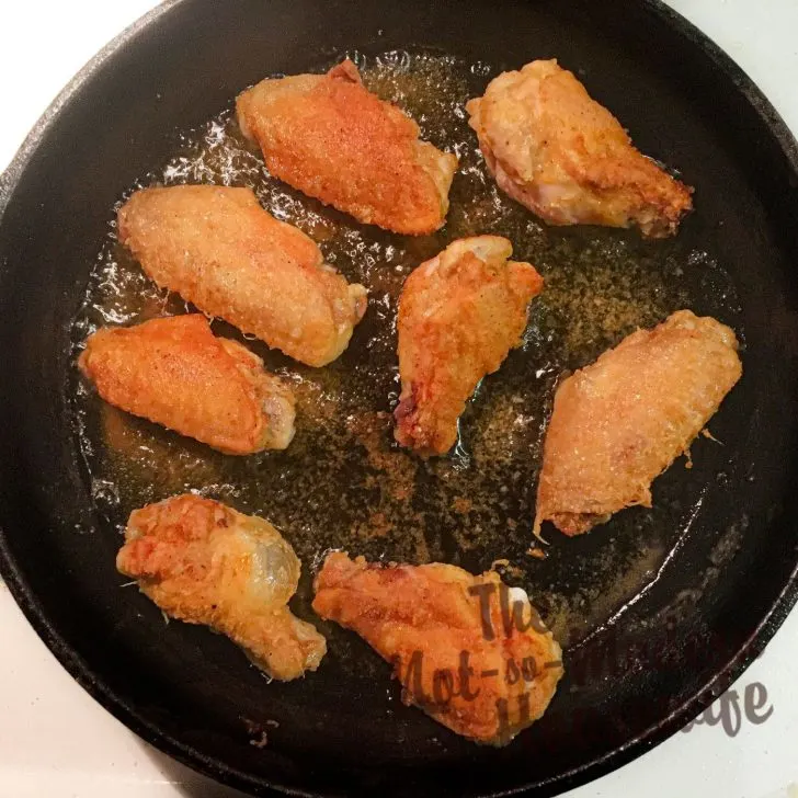 pan frying chicken wings in a cast iron skillet