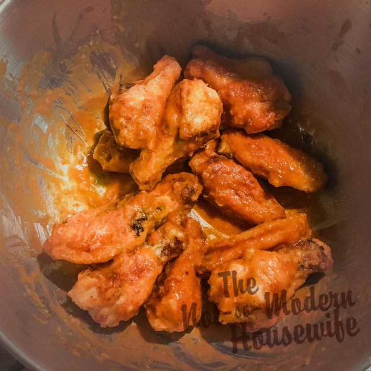 tossing cast iron chicken wings in wing sauce