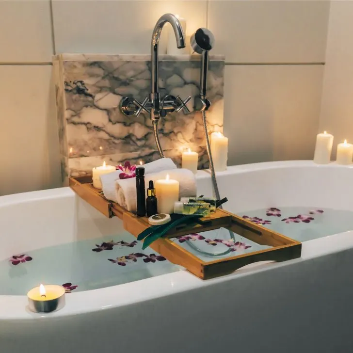 bathtub with flower petals, candles, and spa products - Christmas gift ideas for housewives