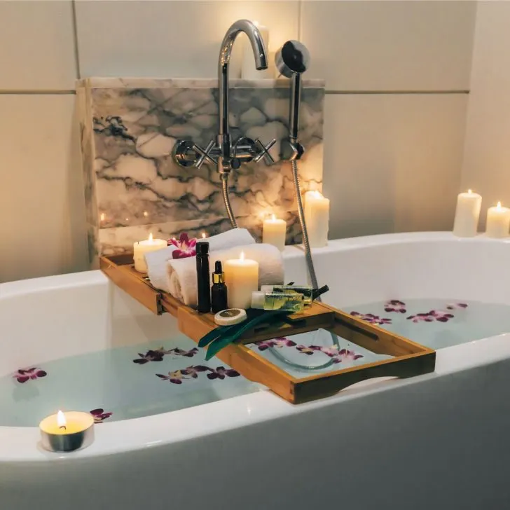 60+ Unexpected Christmas Gift Ideas for Housewives That They Will Truly Cherish | The Not so Modern Housewife bathtub with flower petals, candles, and spa products - Christmas gift ideas for housewives