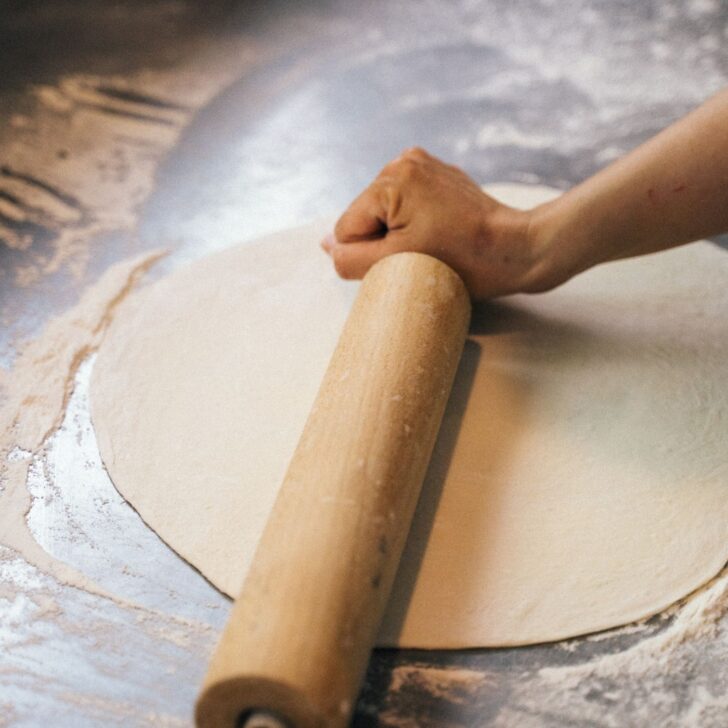 rolling out sourdough pizza dough for even thickness and baking