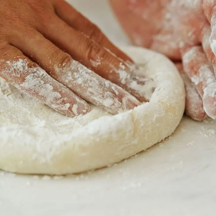 using fingers to press out and shape easy pizza dough