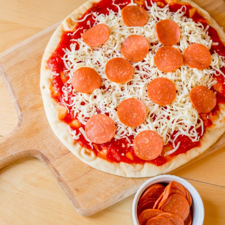 homemade pizza with pepperoni and cheese on a pizza peel